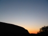 Sunset behind Uluru.  The distant Kata Tjuta nestles beside the base.
