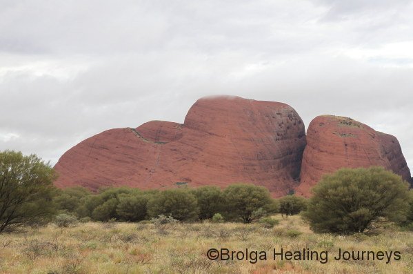 A small cloud brushes the top of Mt Olga, which glistens after morning rain.  Mt Olga is an enormous strucure, rising some 546 metres above the surrounding plains, about 200 metres more than Uluru